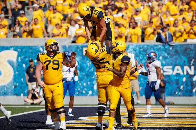 David Sills V #13 of the West Virginia Mountaineers is lifted up by Isaiah Hardy #65 after catching a 17-yard touchdown pass against the Kansas Jayhawks in the fourth quarter of the game at Mountaineer Field on October 6, 2018 in Morgantown, West Virginia. The Mountaineers won 38-22.